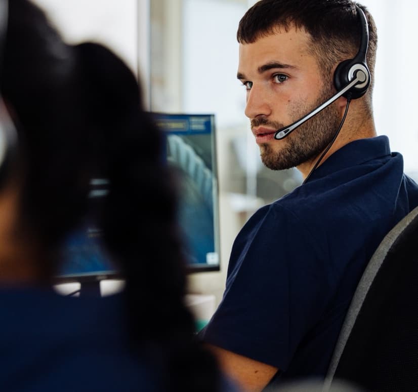 Operatore della Centrale Operativa Sailornet al telefono con auricolare davanti ai monitor